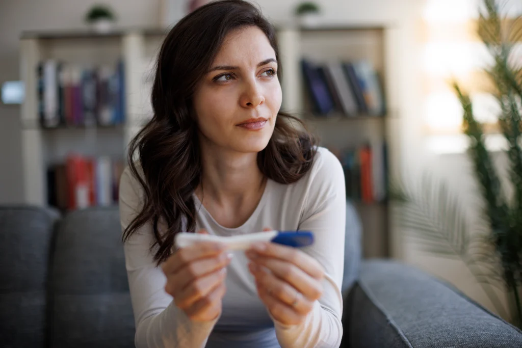 Woman sitting on couch with pregnancy test